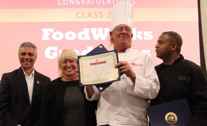 A man in a chef's uniform standing with three other people on graduation day.
