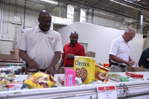 three volunteers sorting food on conveyor belt