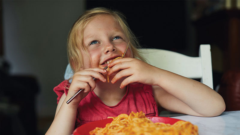 smiling little girl eating spaghetti