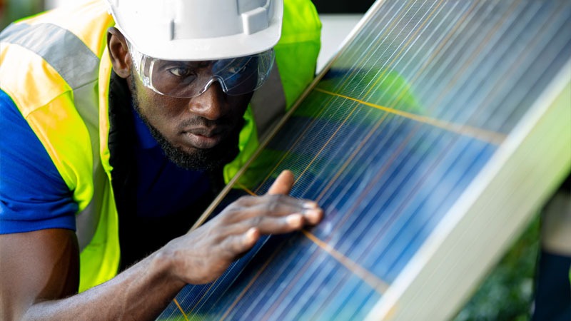 black man inspects solar panel