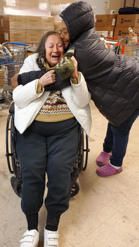 volunteer hugs a neighbor in her wheelchair