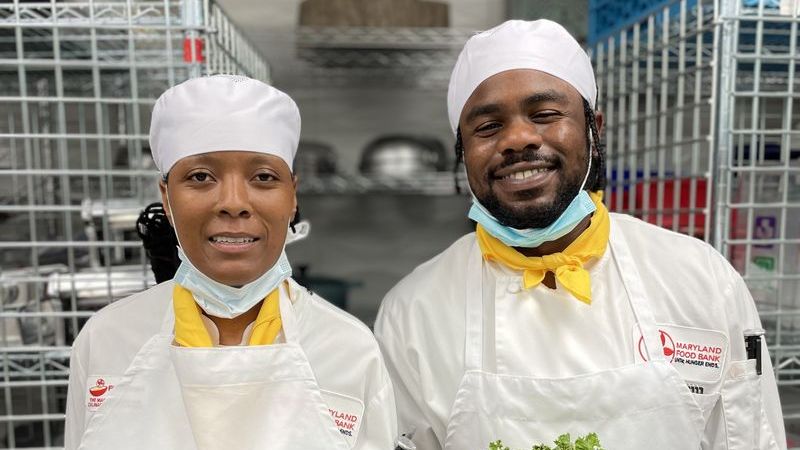 two Foodworks students, one black female, one black male, smiling in a kitchen