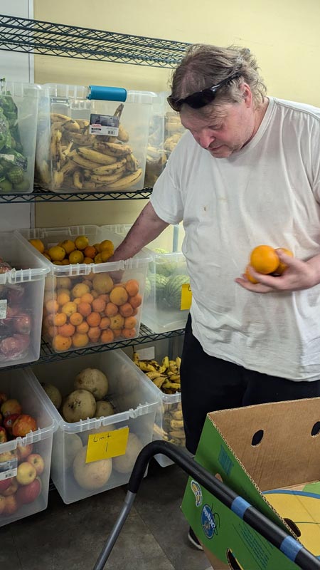 older man picks out oranges from a food distribution event bin