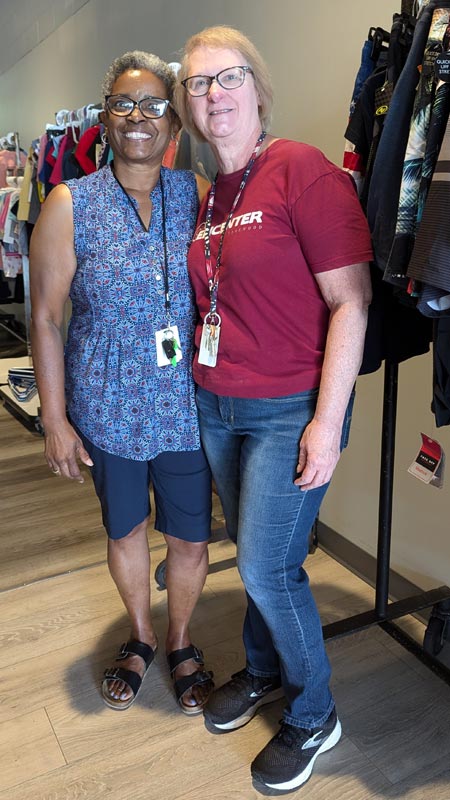 two older women stand among racks of clothing