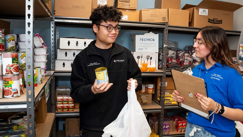 young man gets canned food from a female pantry coordinator