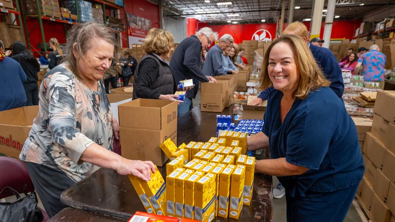 corporate volunteers packing boxes during our Pack To Give Back event