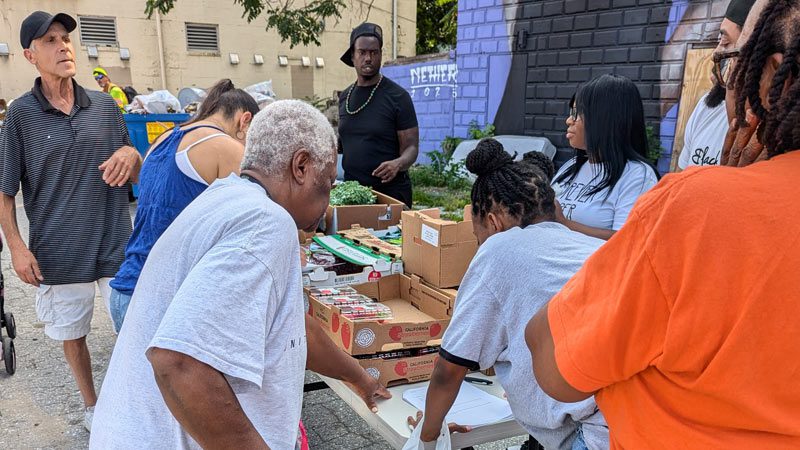 neighbors picking up food items from food distribution table at the Black Yield Institute