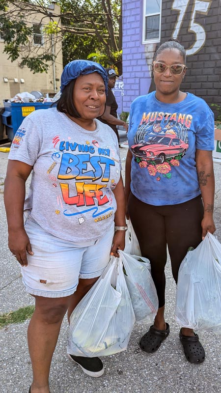 two happy black women picking up food items from food distribution at the Black Yield Institute