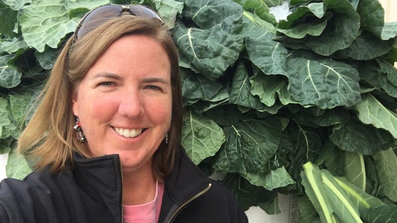 Amy Cawley smiling in front of collard greens