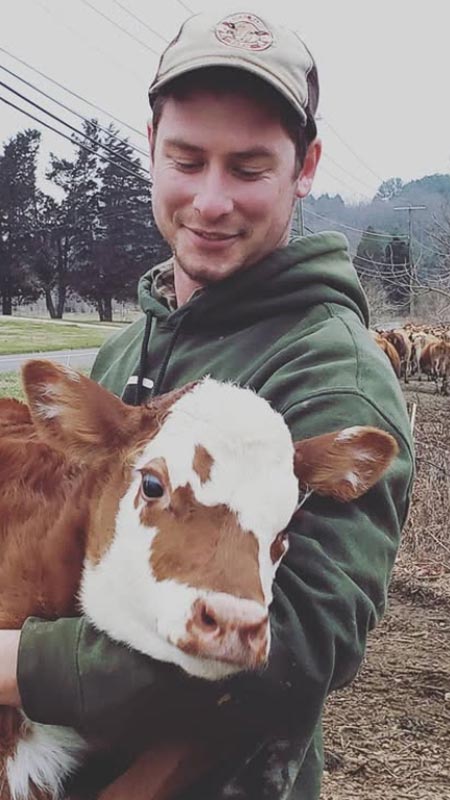 Bellevale Farms farmer holding a brown and white calf