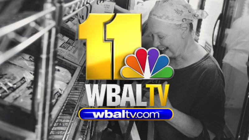 WBAL logo on greyscale image of elderly caucasian woman smiling inside Mobile Market truck