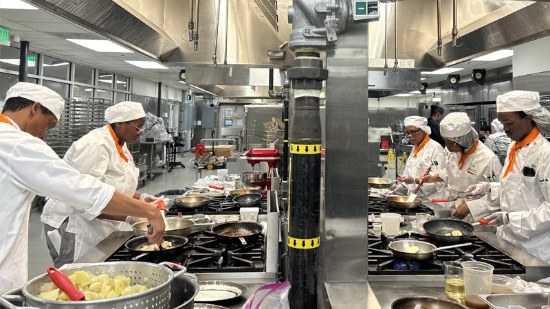FoodWorks students standing at their own stoves preparing food in the kitchen