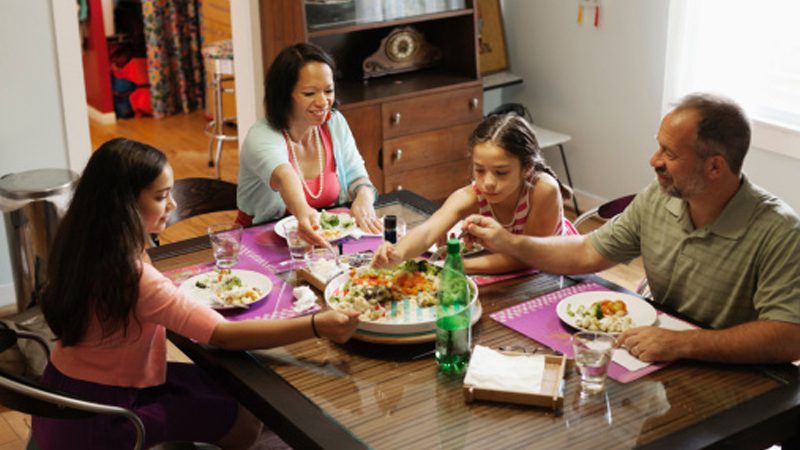 family of four sitting at table for dinner