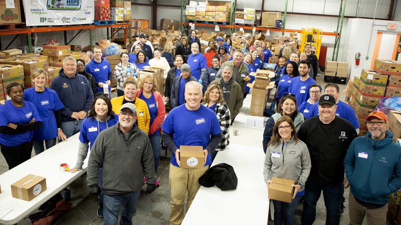 large group of corporate volunteers in the warehouse posing for a photo