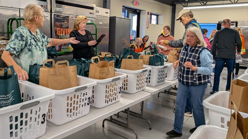 neighbors go thru food distribution line of tables inside Chesapeake Cares facility