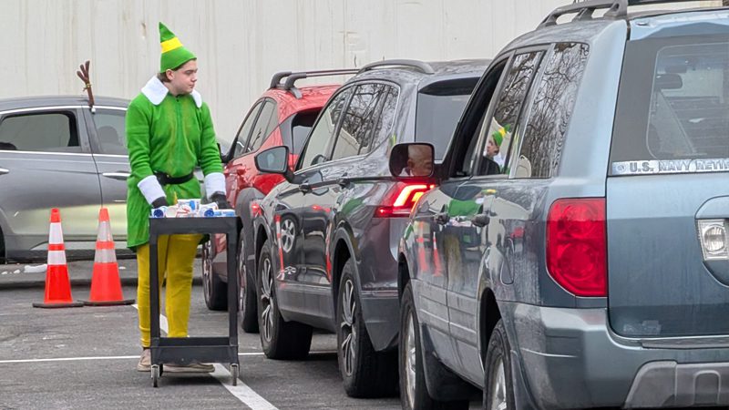 Love Wins volunteer dressed up as an elf while distributing food to line of cars