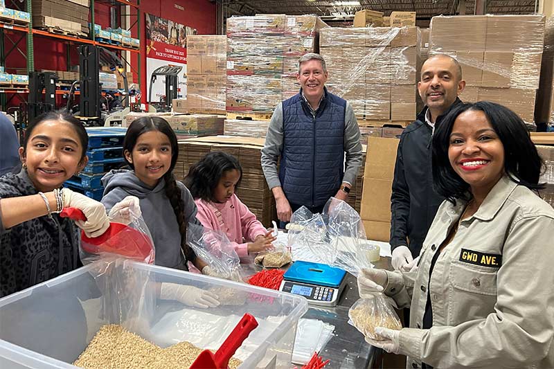 a family of volunteers smile repacking bulk rice during Martin Luther King, Jr. Day of Service event