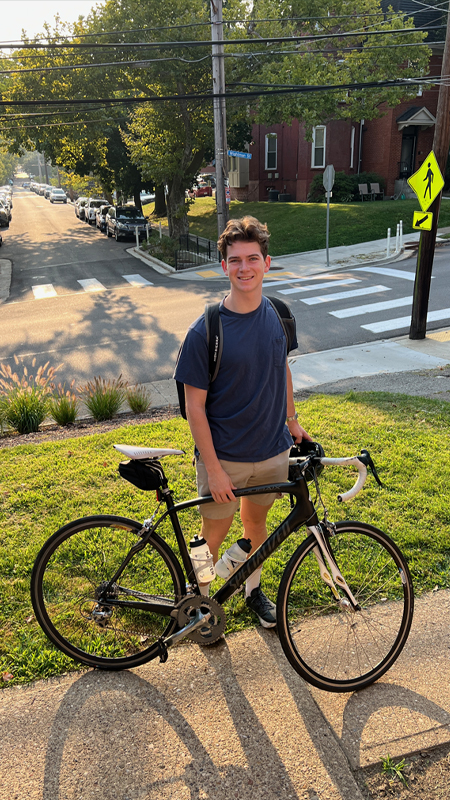 Ryan Walther standing outside in a suburban area with his bike in a dark blue tshirt