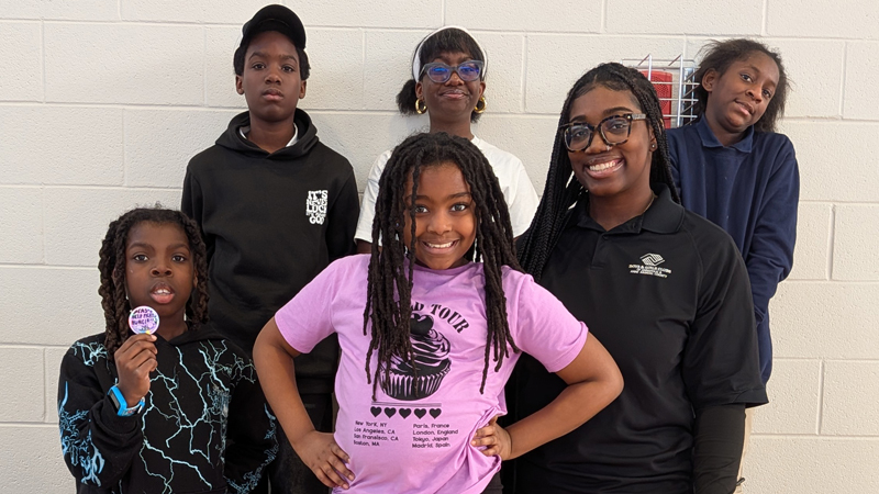 group of school-aged children and their teacher standing in gym posing for a photo